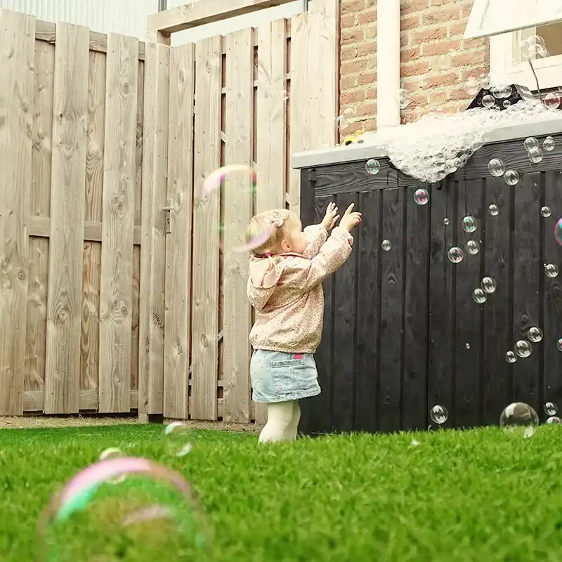 kind-speelt-met-schuim-bubbels-kinderopvang-ark-oss » Kinderopvang & BSO in Oss Een jong kind speelt enthousiast met wit schuim en bellen in een watertafel bij Kindercentrum de Ark in Oss.